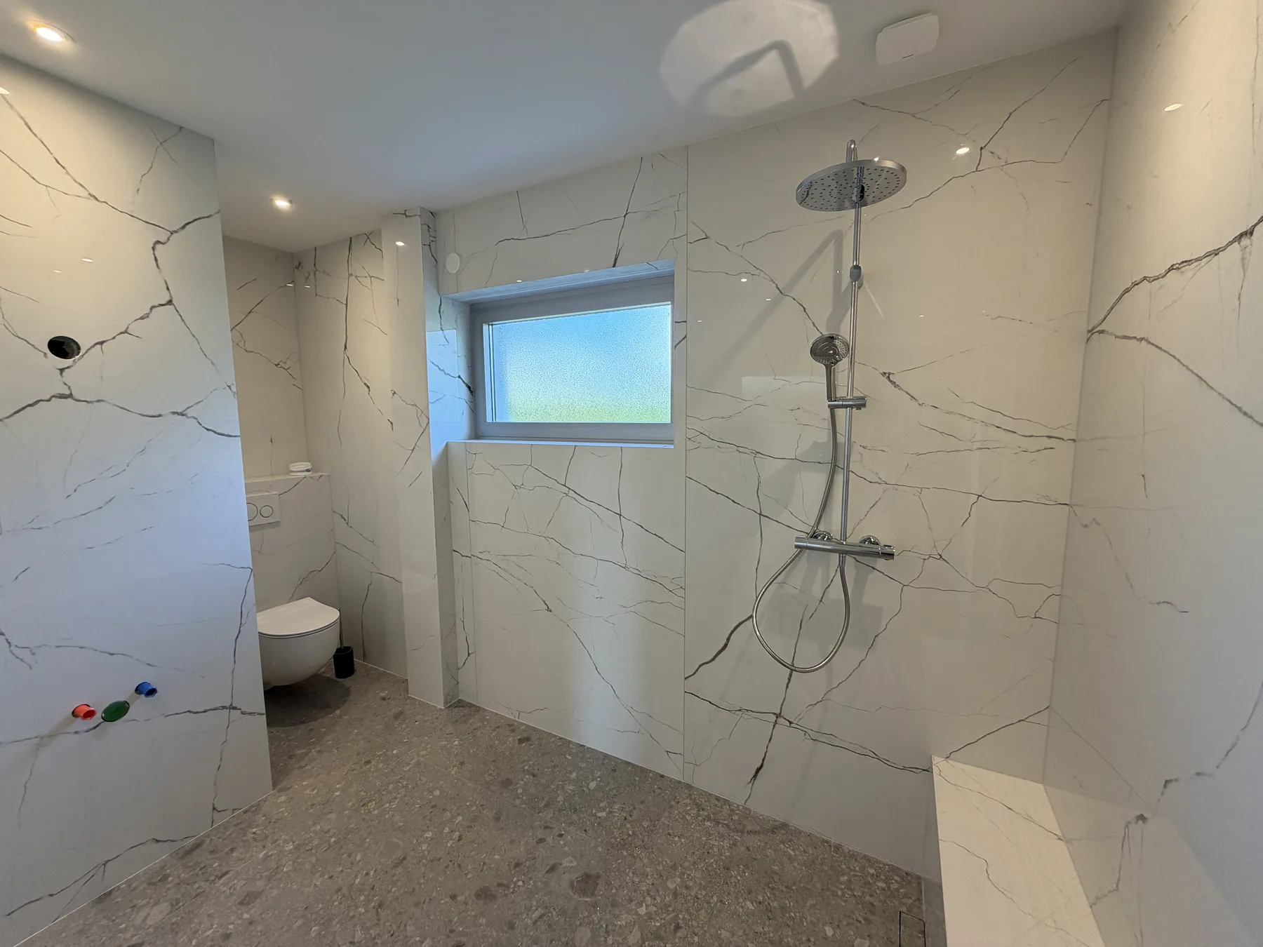Salle de bain en marbre blanc veiné avec douche italienne