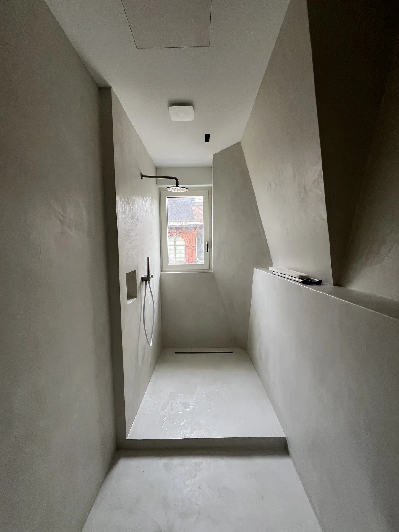 Douche italienne en béton ciré crème sous lucarne